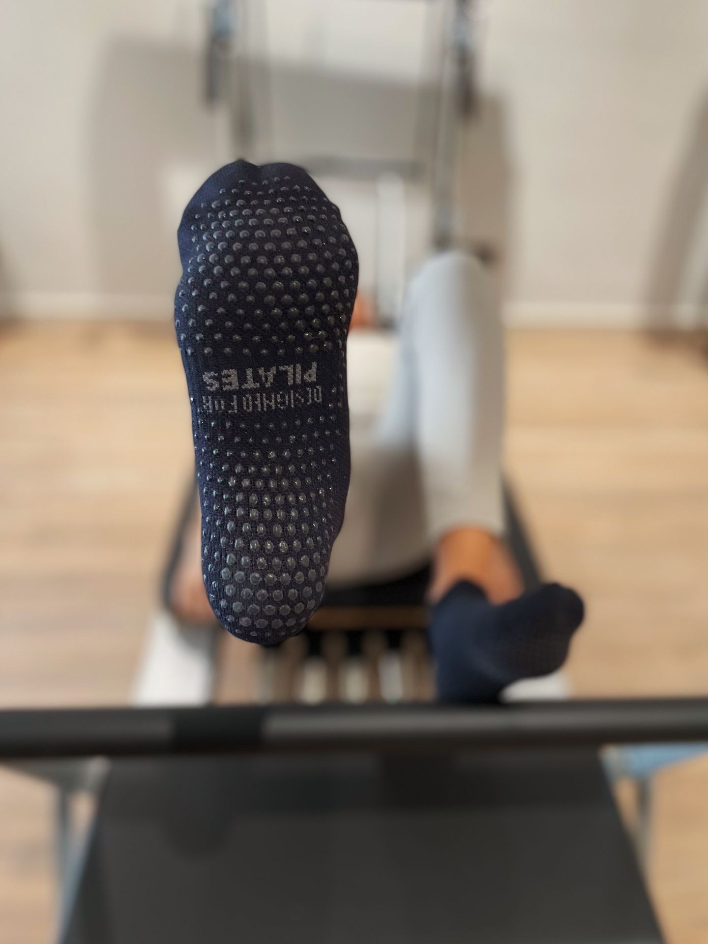 Person performing an exercise on a Pilates reformer with a close-up view of their socks.